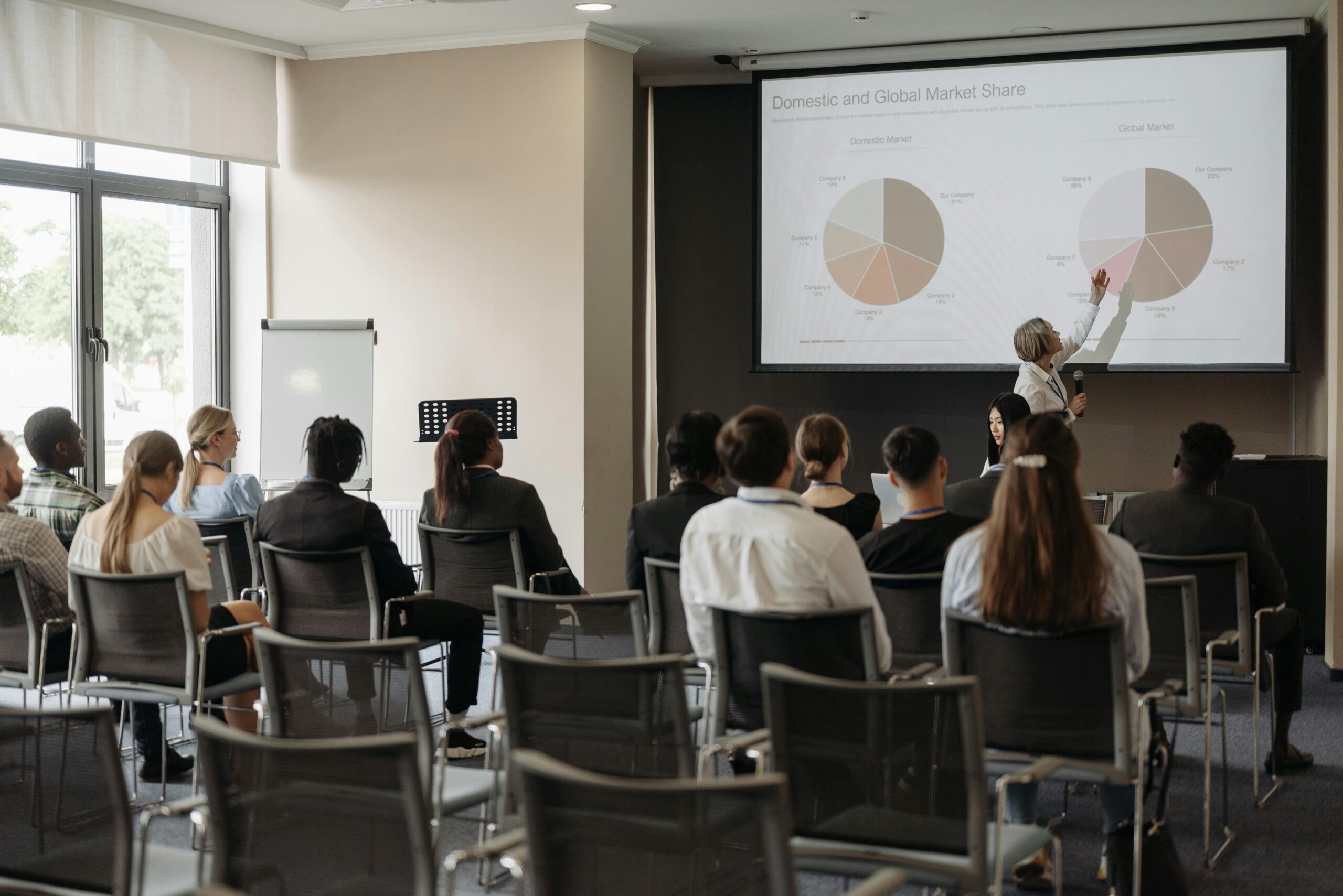 Business professionals attending a seminar with a presentation on market share, highlighting diverse participation.